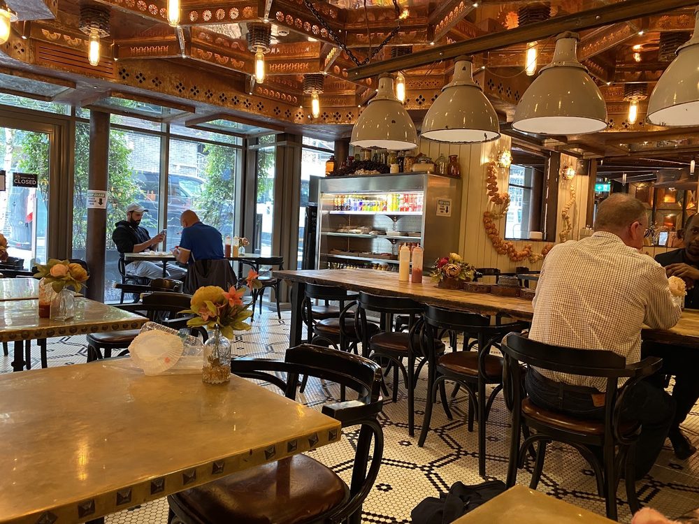 The dining room at The Holmes Cafe looking towards the glass frontage, with bentwood chairs, wooden tables and pendant lights
